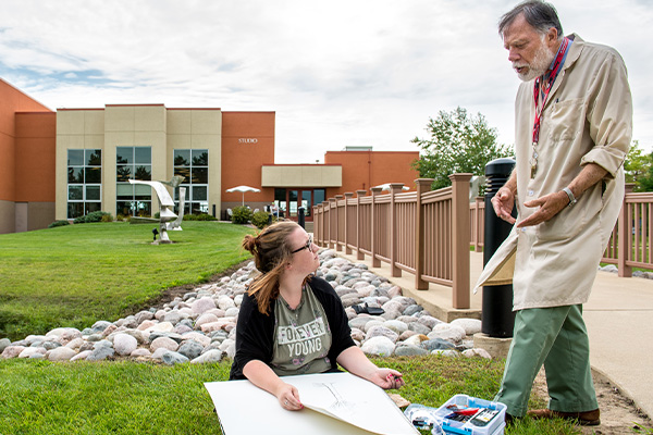 Professor guiding a student when they are drawing